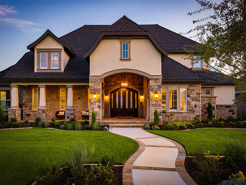 Refined residential exterior with a curved front walk and front entry at dusk